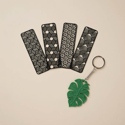 Four black patterned keychains and a green leaf-shaped keychain on a beige background