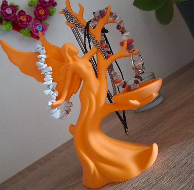 Orange tree-shaped jewelry holder with necklaces on a wooden surface.