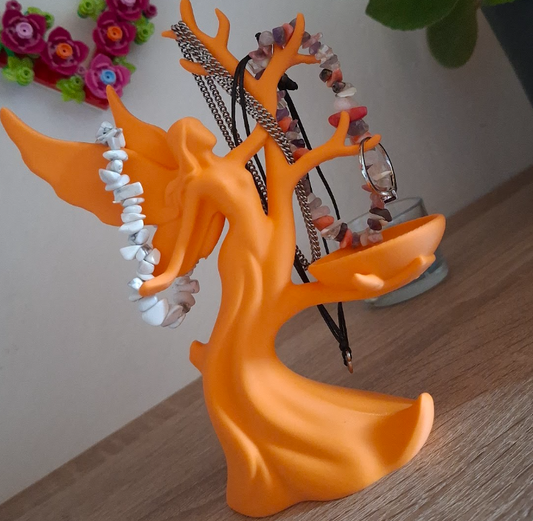 Orange tree-shaped jewelry holder with necklaces on a wooden surface.