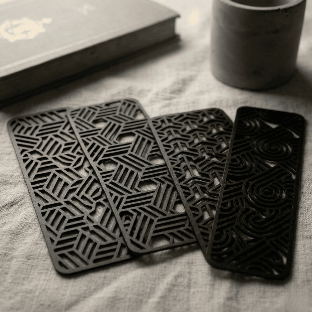 Set of black geometric bookmarks on a textured surface with a book and mug in the background.