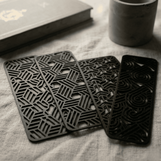 Set of black geometric bookmarks on a textured surface with a book and mug in the background.