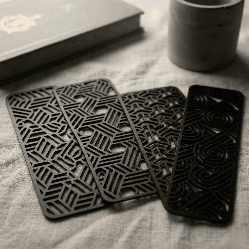 Set of black geometric bookmarks on a textured surface with a book and mug in the background.