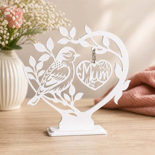Decorative metal stand with a bird and 'Mum' heart design on a wooden surface.