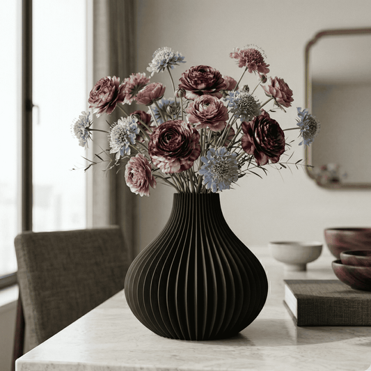 Black vase with flowers on a table in a room